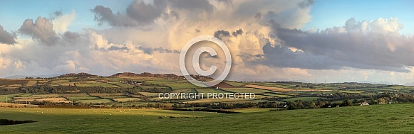 Sunlight on thunder clouds over a rural landscape