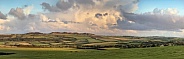 Sunlight on thunder clouds over a rural landscape