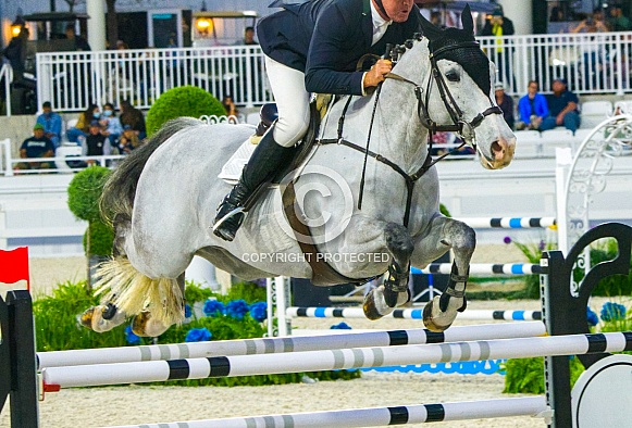 1-30-21 Ocala, Florida. Equestrian Sports, Horse jumping Show free event competition Horse Riding themed photo view of male riding dapple grey horse while jumping over hurdle during an event