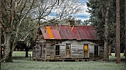 Old, abandoned rustic farmhouse with trees, grass, blue sky with rusty tin roof in North Florida